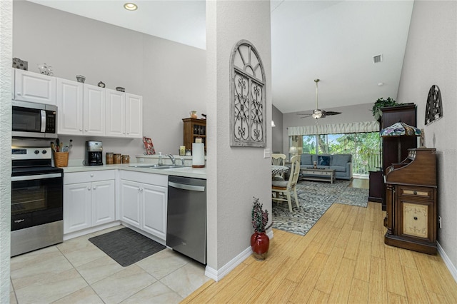 kitchen with appliances with stainless steel finishes, light wood-type flooring, ceiling fan, sink, and white cabinets