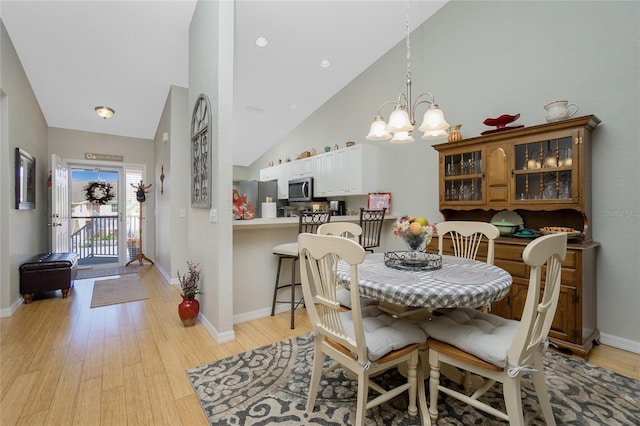 dining area featuring high vaulted ceiling, light hardwood / wood-style floors, and a notable chandelier