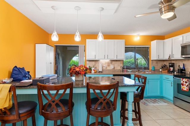 4290 Randypaar St, Port Charlotte, FL 33948 - kitchen featuring appliances with stainless steel finishes, decorative backsplash, a breakfast bar, white cabinets, and hanging light fixtures