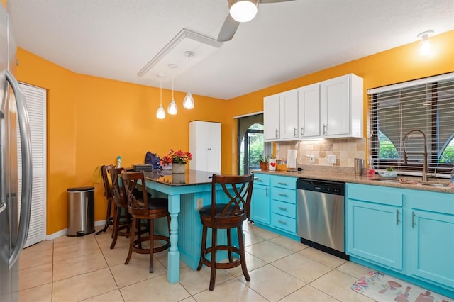 4290 Randypaar St, Port Charlotte, FL 33948 - kitchen with stainless steel appliances, blue cabinets, a breakfast bar, tasteful backsplash, and light tile patterned floors