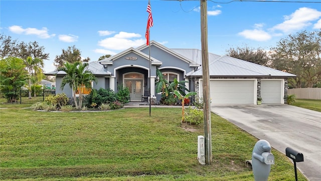 view of front of property with french doors, a garage, and a front lawn