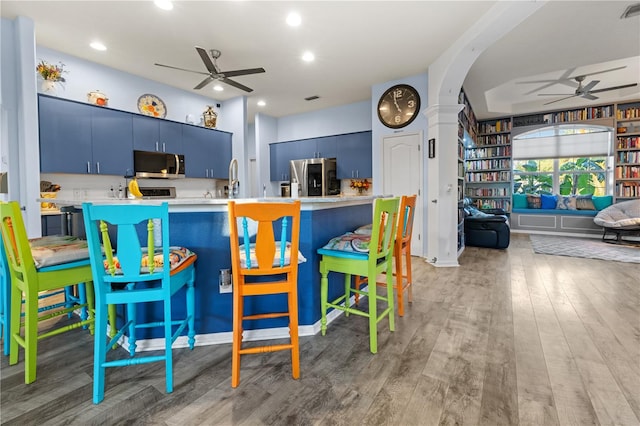 kitchen featuring kitchen peninsula, a kitchen bar, stainless steel appliances, and blue cabinets