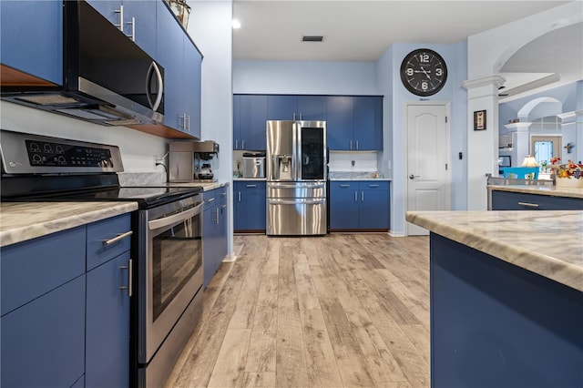 kitchen with stainless steel appliances, blue cabinets, light hardwood / wood-style floors, and ornate columns