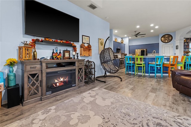 living room featuring light hardwood / wood-style floors, ceiling fan, and sink