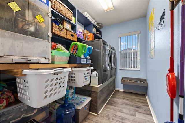 laundry area featuring wood-type flooring, a textured ceiling, and washing machine and clothes dryer