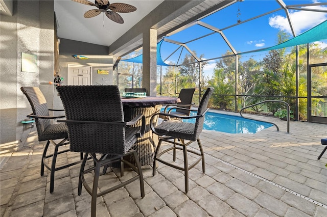 view of swimming pool featuring ceiling fan, a patio area, an outdoor bar, and glass enclosure