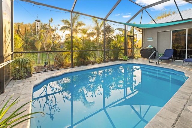 view of swimming pool with a patio area and a lanai