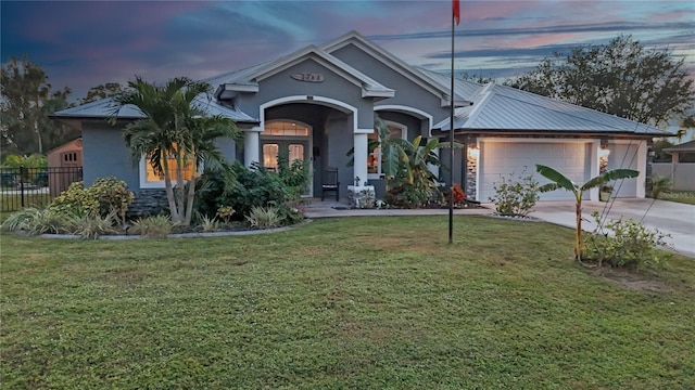 view of front of house featuring french doors, a garage, and a lawn