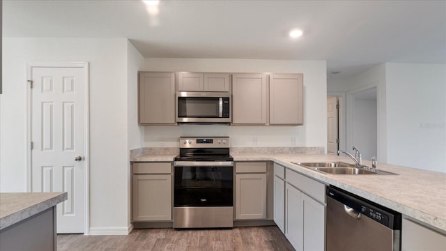 kitchen featuring appliances with stainless steel finishes, light wood-type flooring, gray cabinets, and sink