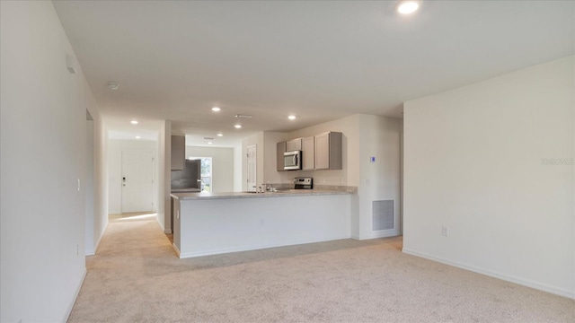 kitchen featuring light stone countertops, stainless steel appliances, gray cabinetry, and light colored carpet