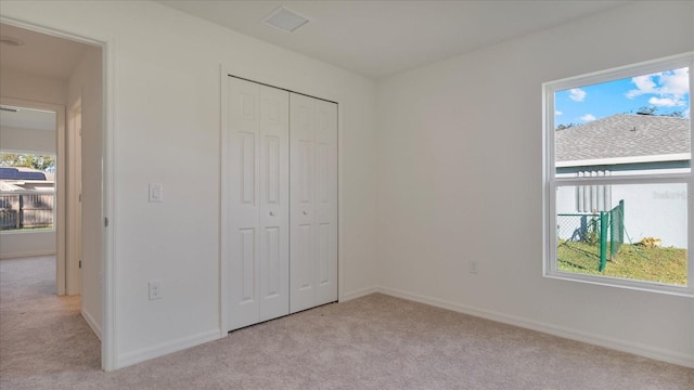 unfurnished bedroom featuring light carpet and a closet