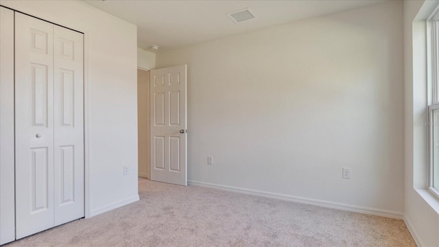 unfurnished bedroom with light colored carpet and a closet