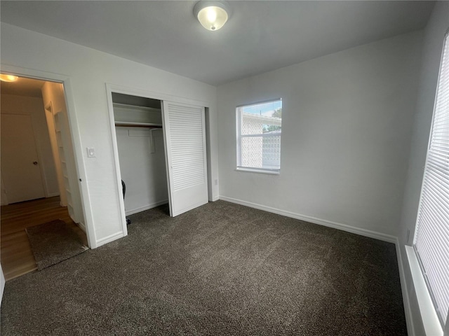 unfurnished bedroom featuring dark carpet and a closet