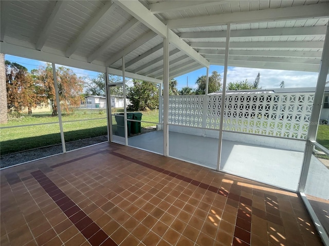 unfurnished sunroom featuring vaulted ceiling with beams