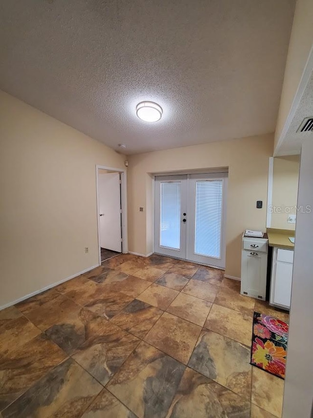 doorway with french doors and a textured ceiling