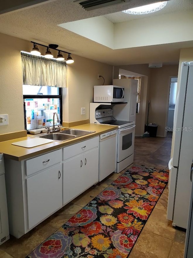 kitchen featuring a textured ceiling, white appliances, white cabinetry, and sink