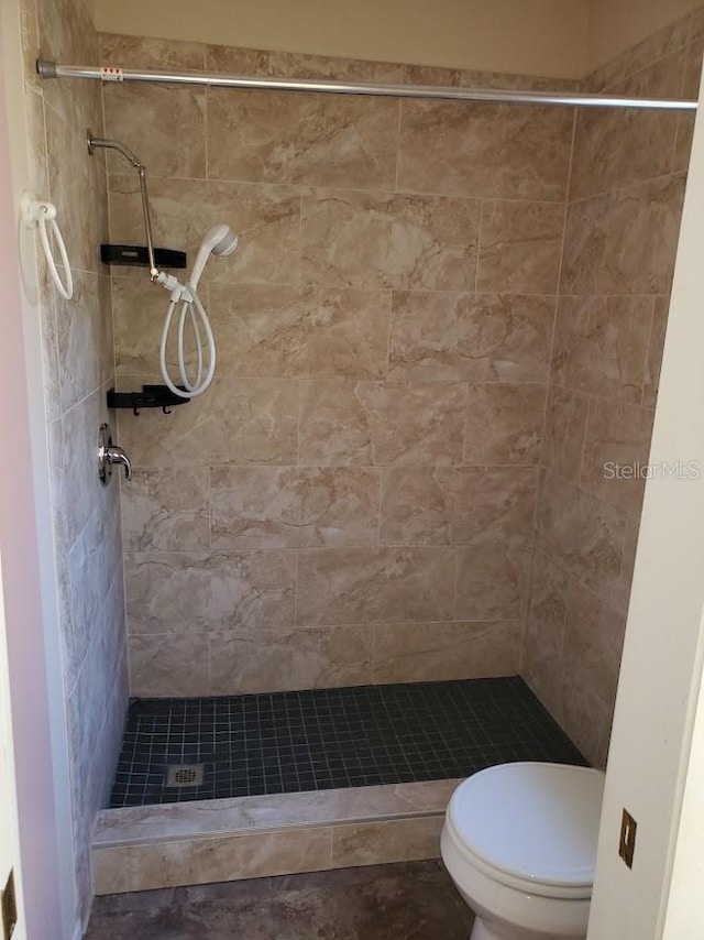 bathroom with a tile shower and toilet