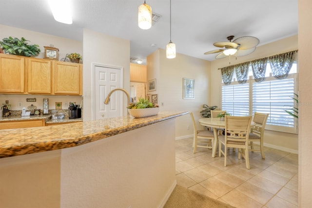 kitchen featuring light stone countertops, light brown cabinetry, ceiling fan, hanging light fixtures, and light tile patterned flooring