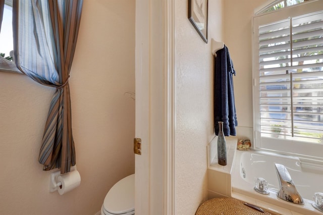 bathroom featuring toilet and tiled tub