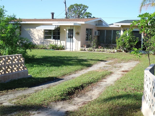 view of front facade featuring a front yard and a wall unit AC