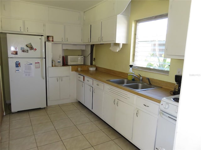 kitchen featuring white cabinetry, sink, light tile patterned flooring, and white appliances