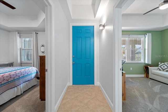 carpeted foyer entrance featuring a tray ceiling and ceiling fan