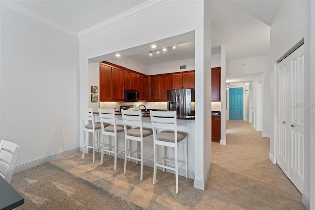 kitchen featuring kitchen peninsula, stainless steel fridge, a kitchen bar, light tile patterned floors, and ornamental molding