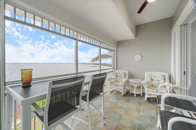 sunroom with a water view and ceiling fan