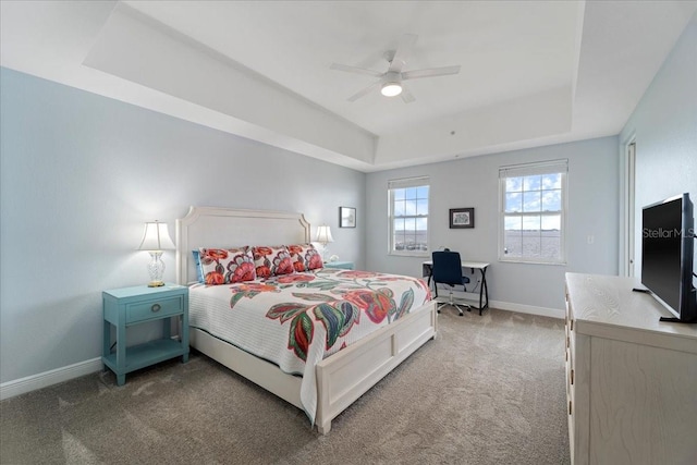 carpeted bedroom featuring a raised ceiling and ceiling fan