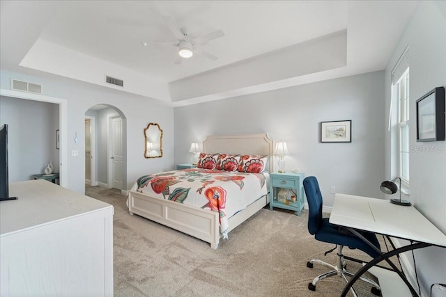 bedroom featuring ceiling fan, light carpet, and a tray ceiling