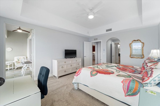 carpeted bedroom featuring ceiling fan and a raised ceiling