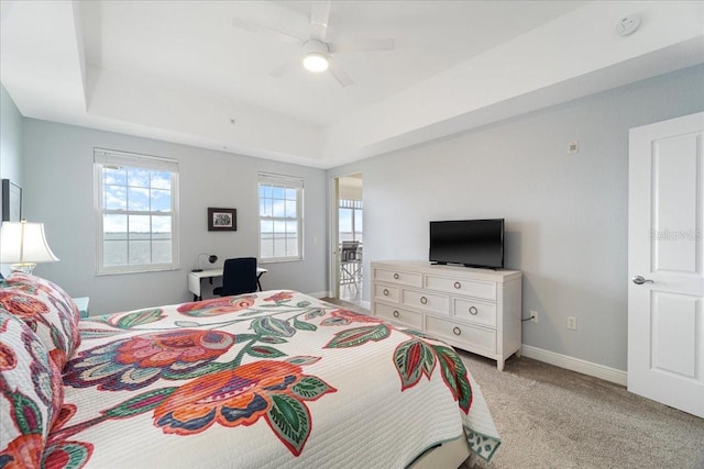 carpeted bedroom featuring a tray ceiling and ceiling fan