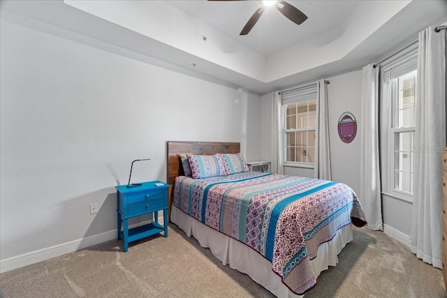 bedroom featuring light colored carpet, ceiling fan, and a tray ceiling