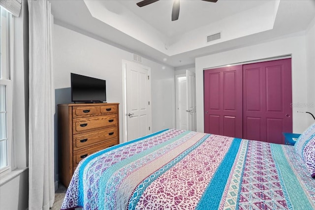 bedroom featuring a raised ceiling, ceiling fan, and a closet