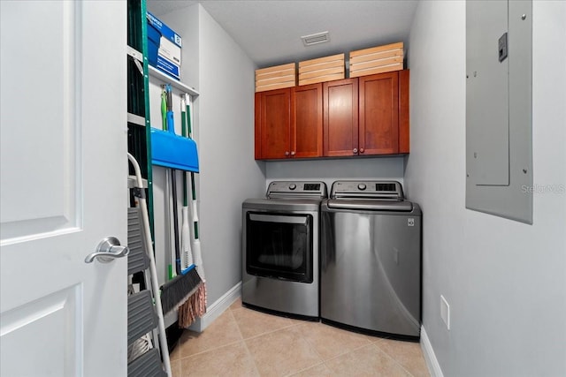 washroom with washing machine and clothes dryer, electric panel, light tile patterned flooring, and cabinets