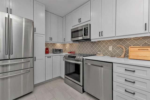 kitchen featuring backsplash, white cabinetry, light tile patterned floors, and stainless steel appliances