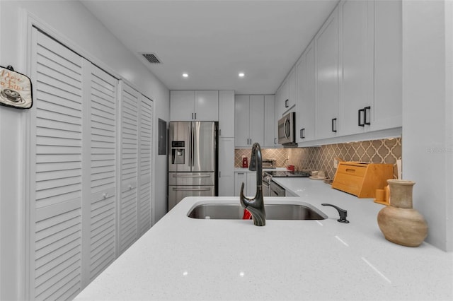 kitchen with white cabinets, stainless steel appliances, tasteful backsplash, and sink