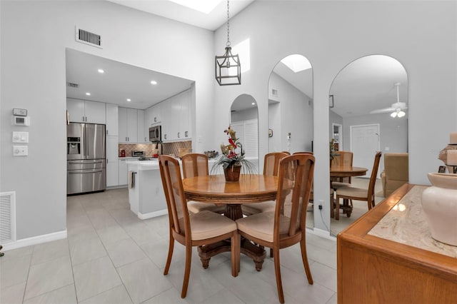 tiled dining space featuring a high ceiling and ceiling fan