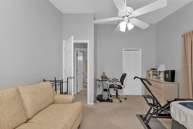 interior space featuring a high ceiling, light colored carpet, and ceiling fan