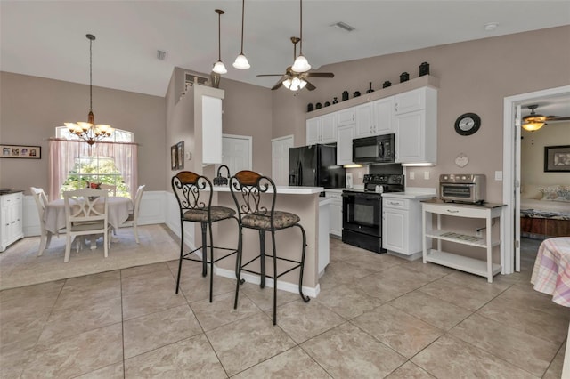 kitchen featuring a kitchen breakfast bar, ceiling fan with notable chandelier, black appliances, light tile patterned floors, and white cabinetry