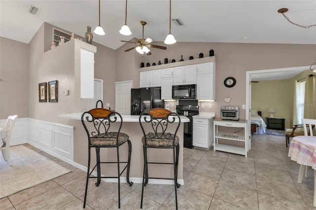 kitchen with kitchen peninsula, white cabinets, black appliances, and lofted ceiling