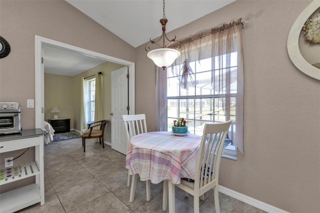 tiled dining room featuring lofted ceiling