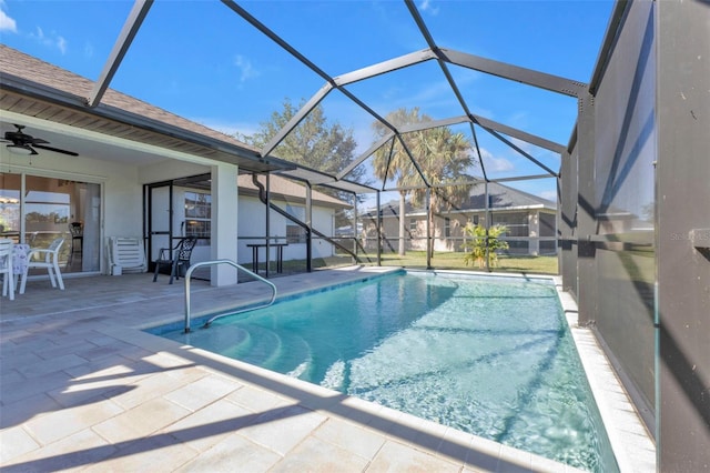 view of pool with glass enclosure, ceiling fan, and a patio area