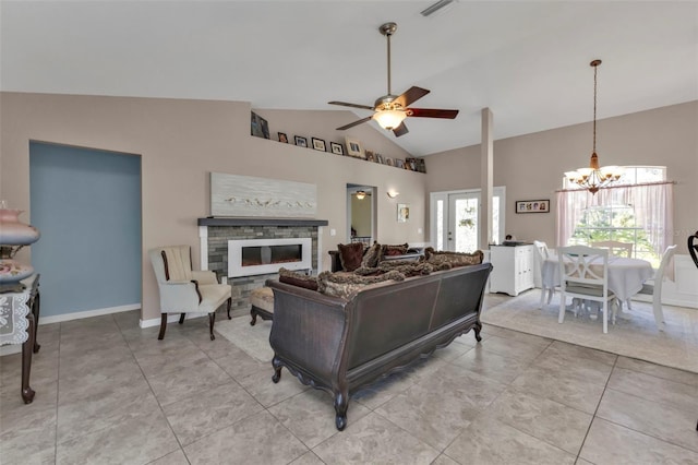 living room with light tile patterned floors, baseboards, high vaulted ceiling, a stone fireplace, and ceiling fan with notable chandelier