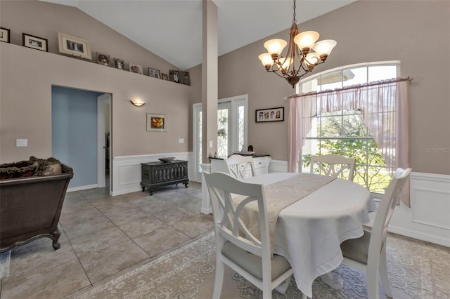 dining space featuring a wainscoted wall, high vaulted ceiling, light tile patterned flooring, a decorative wall, and a chandelier