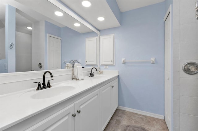 bathroom with double vanity, recessed lighting, baseboards, and a sink
