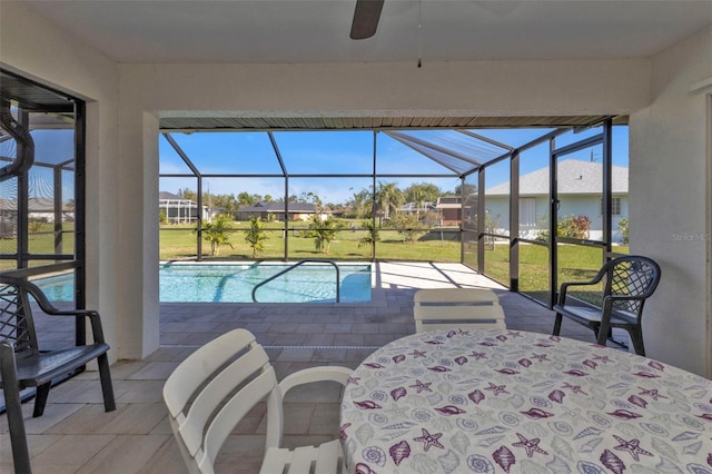 exterior space featuring glass enclosure, outdoor dining area, ceiling fan, a patio area, and a lawn