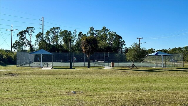 view of community with a lawn, a tennis court, and fence