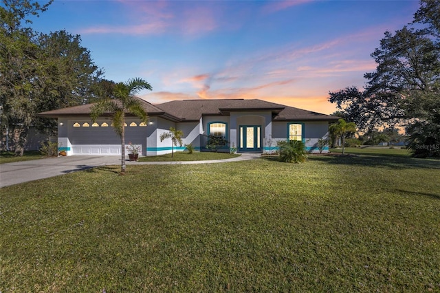 view of front of home featuring concrete driveway, an attached garage, a lawn, and stucco siding