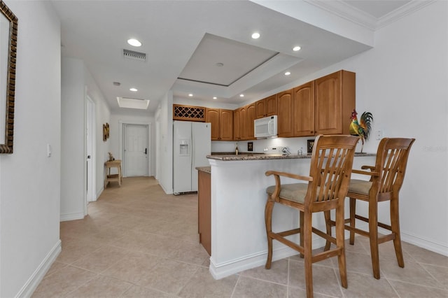 kitchen with white appliances, ornamental molding, light tile patterned flooring, a kitchen bar, and kitchen peninsula